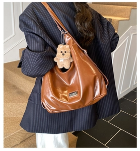 Detail of vintage brown leather tote bag with a cute plush dog pendant and metal tag