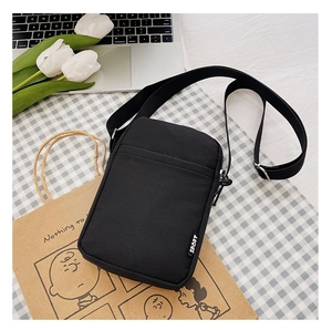 Detail view of black nylon crossbody phone bag with adjustable strap and Sport label