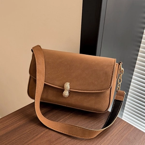 Minimalist brown suede crossbody bag featuring a unique golden peanut-shaped buckle closure