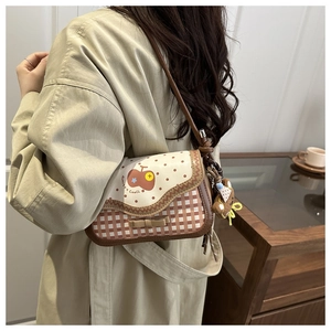 Detail of checkered shoulder bag featuring a cute bear pendant and apple pattern print