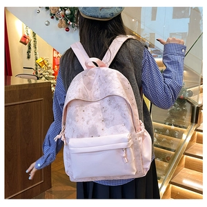 Close-up of pink backpack with star and moon patterns on a person's back in a room