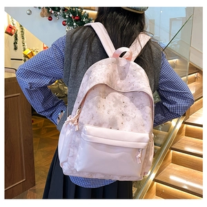 Pink backpack with star and moon patterns shown from a back-view on a model