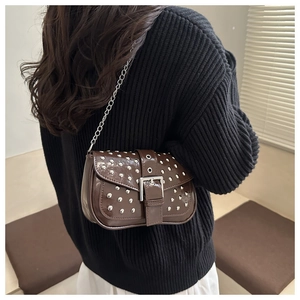 Detail of brown patent leather crossbody bag with silver punk studs and chain strap