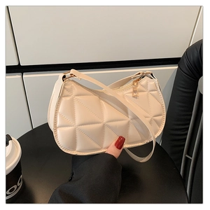 Détail de la texture matelassée blanche et de la fermeture éclair dorée du sac chic