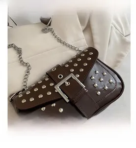 Detail of dark brown leather punk bag with silver studs and a large metal buckle