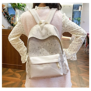 Detailed close-up of a cream backpack featuring star and moon prints with knotted zipper pulls