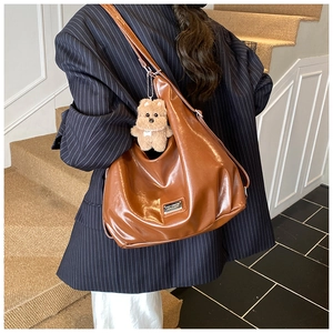 Detail view of brown large capacity tote bag with adjustable strap and plush puppy charm