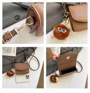 Detail view of brown pebbled leather mini crossbody bag with cute plush monster charm