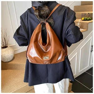 Brown glossy PU leather Hobo bag shown on shoulder with stylish crescent shape