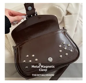 Close-up of the silver magnetic snap closure and studs on a dark brown punk style handbag