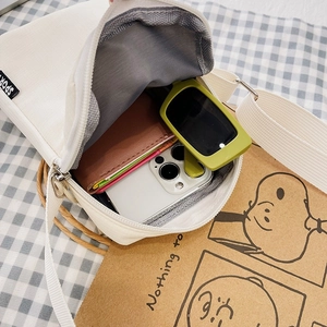 White nylon crossbody phone bag showing interior capacity with wallet and phone