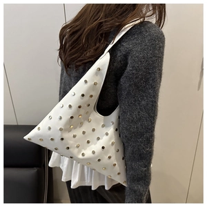 Détail d'un sac sous le bras en cuir blanc triangulaire avec des clous dorés élégants