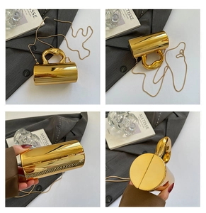 Detail of a golden cylindrical evening bag with a metallic finish and artistic handle