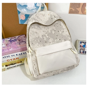 Close-up of beige backpack with star and moon prints featuring a large front pocket
