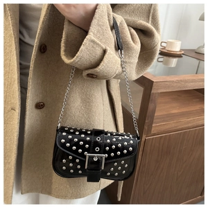 Detail of a black patent leather shoulder bag with silver rivets and metallic chain strap