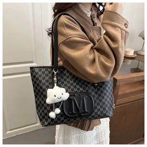 Detailed close-up of black tote bag with M-pattern print and white cloud charm