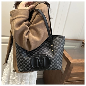 Close-up of black and grey M-letter pattern tote bag with embossed leather logo patch