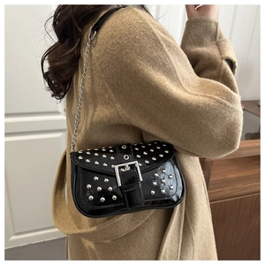 Detail of black patent leather crossbody bag with silver punk rivets and chain strap