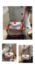 Detailed close-up of plaid girl bag with red apple print and cute bear charm accessory