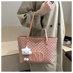 Pink tote bag with monogram M print and cute cloud plush charm shown on a model's shoulder