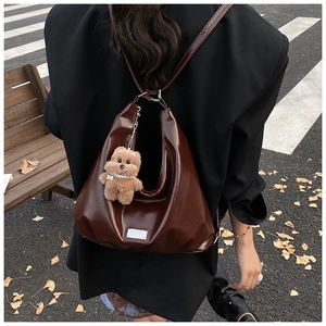 Detailed back view of glossy dark brown leather hobo bag with a plush bear charm on strap