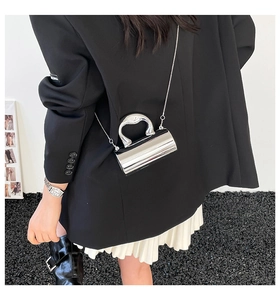 Detail of silver mirror cylinder handbag with unique metal handle and chain strap