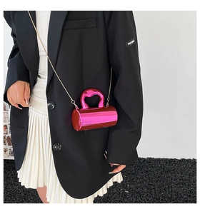 Detail of metallic magenta cylinder bag with heart-shaped cutout handle and gold chain