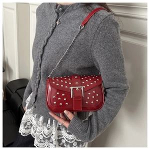Detail of red punk shoulder bag featuring silver rivets and large metal buckle