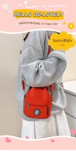 Detail of vibrant orange nylon crossbody bag with front zipper pocket and round logo patch