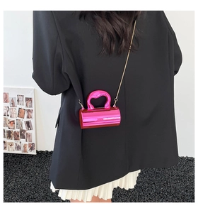 Model view showing the hot pink cylindrical chain bag paired with a black blazer