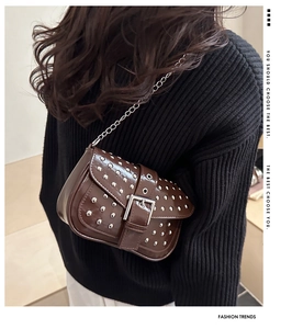 Detail view of brown patent leather crossbody bag with silver punk rivets and chain strap