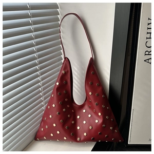 Gros plan du sac Hobo en cuir rouge avec rivets dorés et détails cloutés industriels