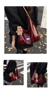 Detail of burgundy tote bag with silver plate and plush bear charm on autumn street