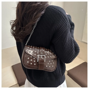 Detail of a vintage punk shoulder bag with silver studs and a chain strap on a model