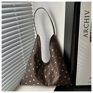 Détail du sac hobo marron foncé avec rivets dorés et silhouette triangulaire minimaliste