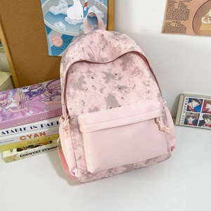 Pink school backpack with moon star print featuring multiple pockets on study desk