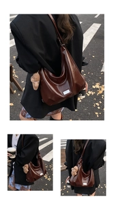 Detail of a dark brown glossy leather hobo bag with a cute plush bear pendant and metal logo