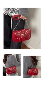 Detail of red punk rivet crossbody bag featuring shiny leather and silver chain strap
