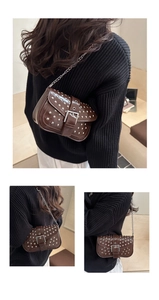 Detail of a punk style dark brown crossbody bag with silver studs and chain strap