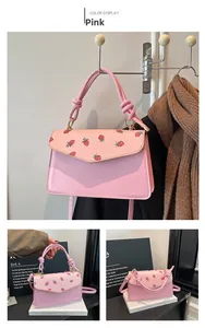 Detail of pink strawberry print crossbody bag with unique knotted handle and flap design