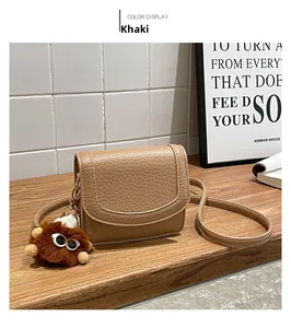 Detail view of khaki crossbody square bag with a brown plush monster pendant