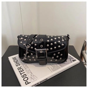 Detailed macro view of black patent leather shoulder bag with silver punk rivets and chain