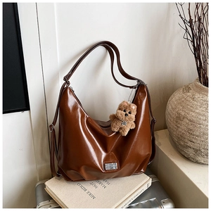 Detail of vintage brown semi-circle PU crossbody bag with cute plush bear charm