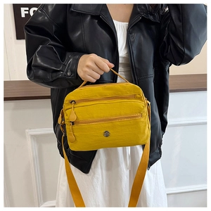 Close-up of yellow water-resistant nylon crossbody bag with multi-layer zipper pockets