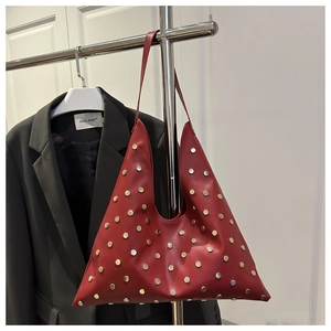 Vue détaillée du sac triangle en cuir rouge orné de rivets métalliques dorés et argentés