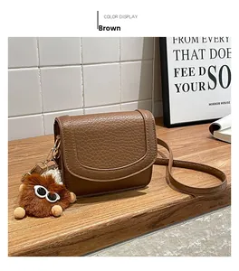 Brown textured leather crossbody bag with U-shaped flap and cute furry monster pendant