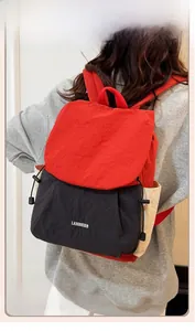 Close-up of lightweight nylon backpack with red contrast flap and black drawstring body