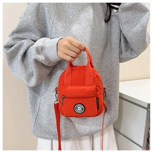 Detailed shot of an orange nylon crossbody bag with adjustable strap on a female model