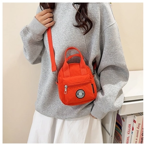 Detailed close-up of a vibrant orange canvas crossbody bag with adjustable strap and handles