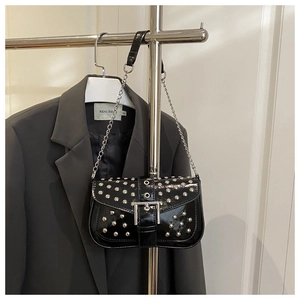 Detail of black patent leather baguette bag featuring silver studs and metal buckle strap